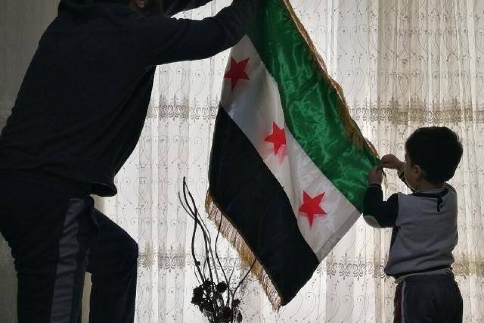 Monther Etaky hänger upp den syriska självständighetsflaggan i Aleppo 2016.