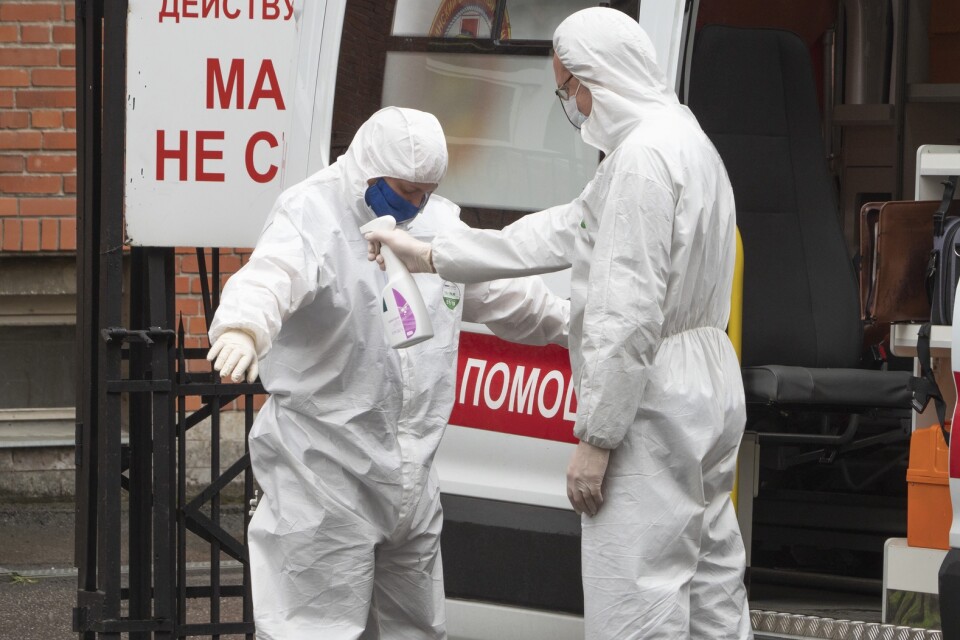 Sjukvårdspersonal som just har transporterat en covid-19-sjuk patient hjälper varandra med skyddsutrustning i S:t Petersburg i Ryssland.