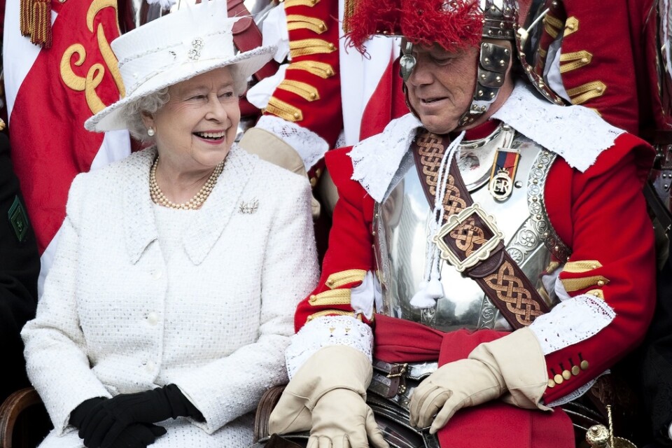 Elizabeth tillsammans med major Paul Champness, ledare för frivilligkompaniet Honorable Artillery, i London i maj 2010. De skrattar gott åt att drottningen hade råkat trassla in sig i majorens 1600-talsuniform.