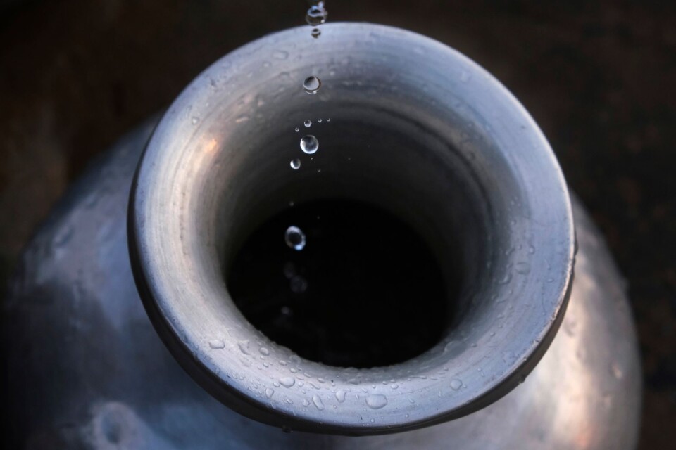 Water drops fall from a hand pump into a vessel.