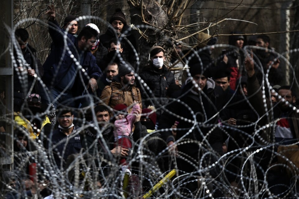 Migranter bakom en avspärrning nära den grekisk-turkiska gränsen i Kastanies.