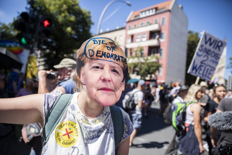 En demonstrant har skrivit orden "hej då demokrati" på en mask föreställande den tyska förbundskanslern Angela Merkel.