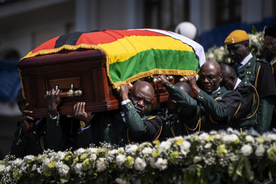 Robert Mugabes kista bärs fram till en helikopter för att fraktas till fotbollsstadion.