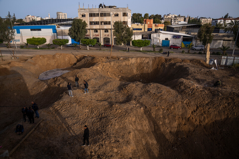 Palestinier i Gaza betraktar en krater som uppstod i israeliska flyganfall under natten.