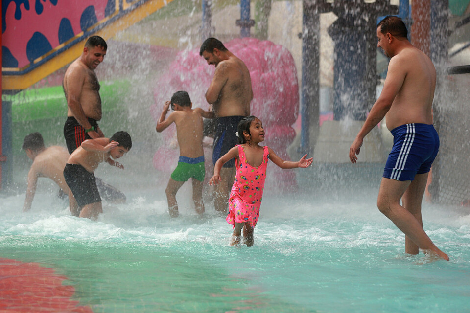 Pappor och barn svalkar sig på ett vattenland i Bagdad. Bilden är från tidigare i veckan.