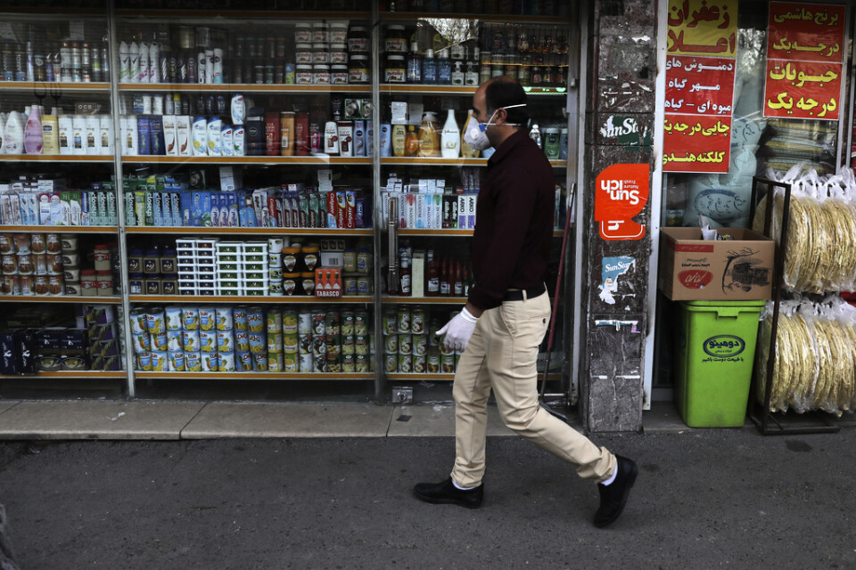 En man med handskar och skyddsmask utanför en butik i Teheran. Arkivbild.