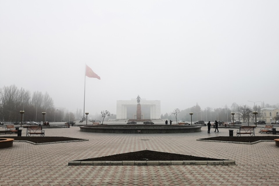 På det centrala torget Ala-Too vajar den kirgiziska flaggan i den tjocka smogen.