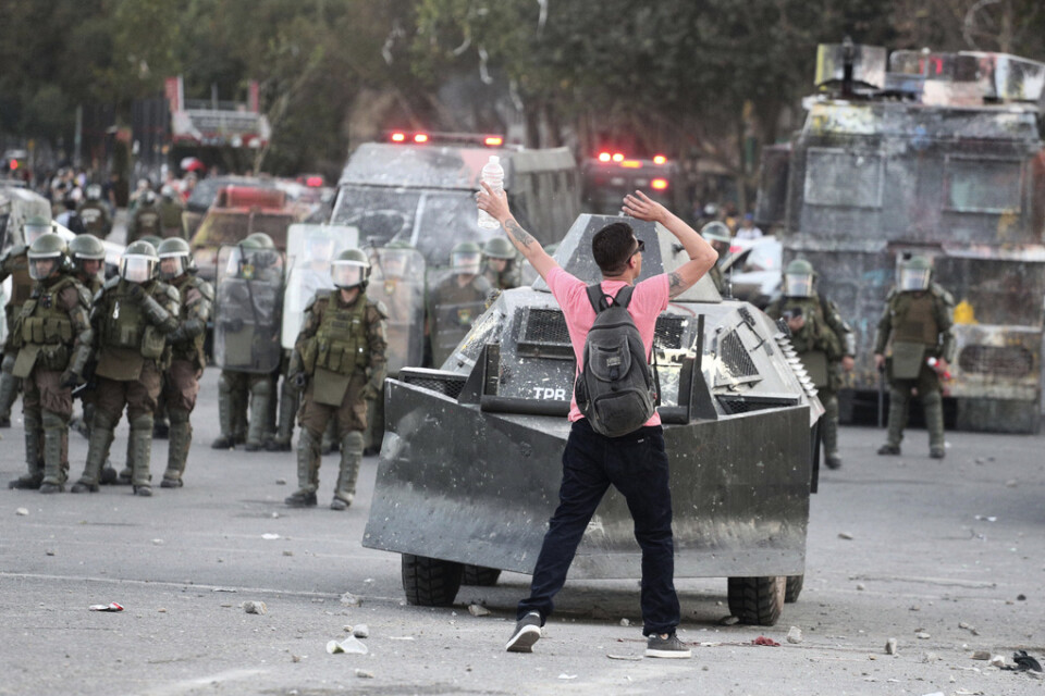En demonstrant framför ett polisfordon under protester i Chiles huvudstad Santiago den 19 november.