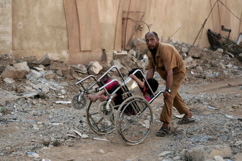 En man drar två små barn i en rullstol för att försöka fly undan striderna mellan irakiska trupper och Islamiska staten innan de drevs ut från Mosul. Totalt bedöms runt 11 000 personer omkommit i striderna om staden.