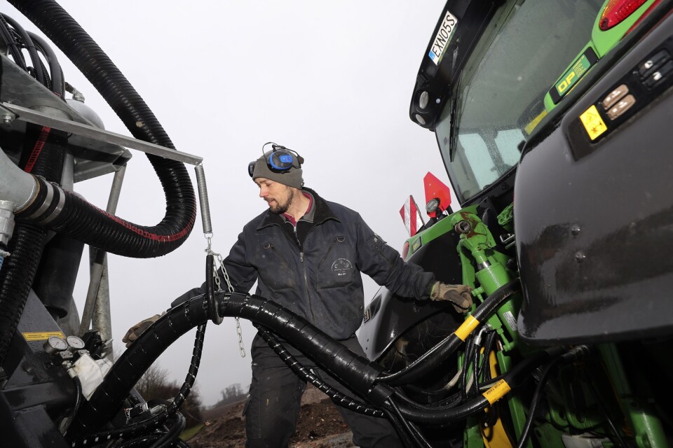 Martin Andersson kopplar hydraulslangar mellan traktorn och gödseltunnan.