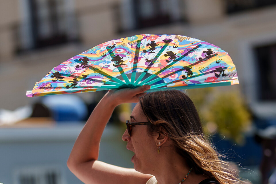 En kvinna i Madrid skyddar sig mot solen. Temperaturen stiger i landet när landets andra värmebölja i sommar drar in.