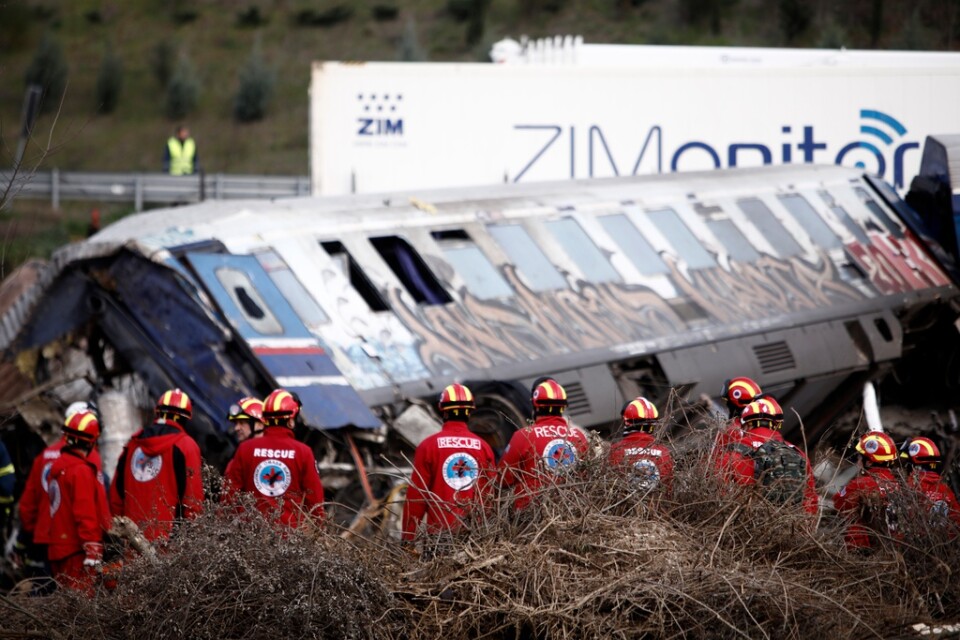 Räddningsarbetare invid en demolerad tågvagn efter den svåra tågolyckan natten mellan tisdag en och onsdagen i Grekland.