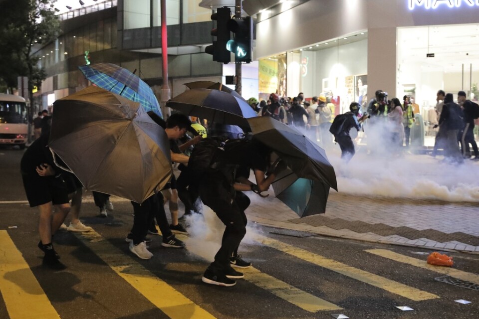Aktivister skyddar sig mot tårgas med paraplyer.