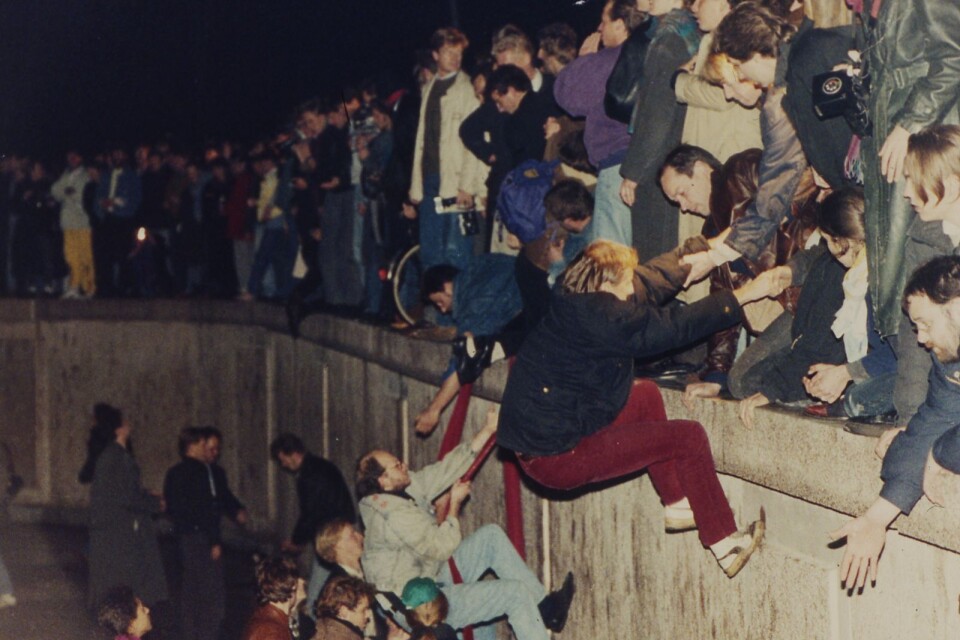 Berlinmuren öppnas den 9 november 1989 och folkmassorna klättrar över muren.