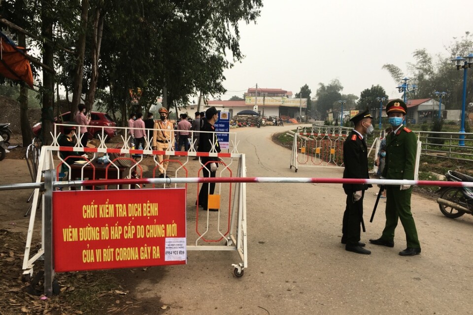 Poliser på vakt vid en vägspärr vid Son Loi utanför Vietnams huvudstad Hanoi under torsdagen. Området är försatt i karantän sedan sex fall av coronaviruset covid-19 upptäckts där.
