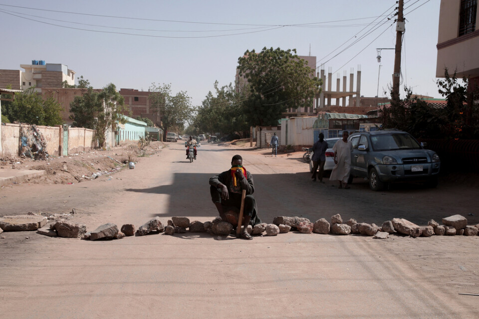 En man bevakar en av de uppbyggda barrikaderna i Sudan, här i Khartum på tisdagen.