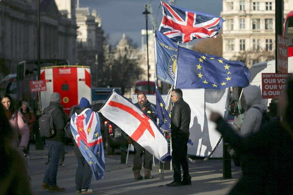 Anti-Brexit protesters wave flags outside the Houses of Parliament, in London, Wednesday December 12, 2018. British Conservative lawmakers forced a no-confidence vote in Prime Minister Theresa May for Wednesday, throwing U.K. politics deeper into crisis and Brexit further into doubt. (AP Photo/Tim Ireland)
