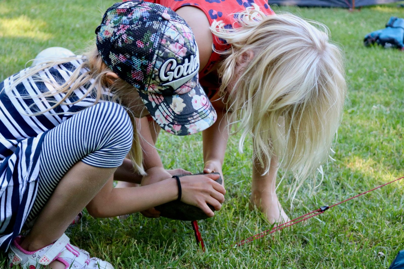 Noelia Medhammar-Nerén och Signe Lindquist använder en sten för att få ner tältpinnarna ordentligt i marken.
