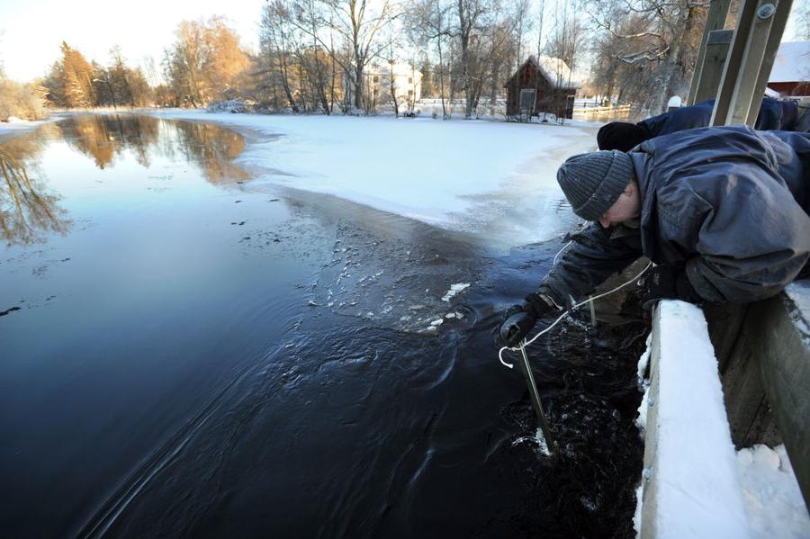 Ett febrilt arbete med att hålla de öppna luckorna hyfsat isfria så att vattnet kunde forsa genom. Ove Pettersson lutar sig så långt ut han vågar utan att riskera hamna i vattnet.