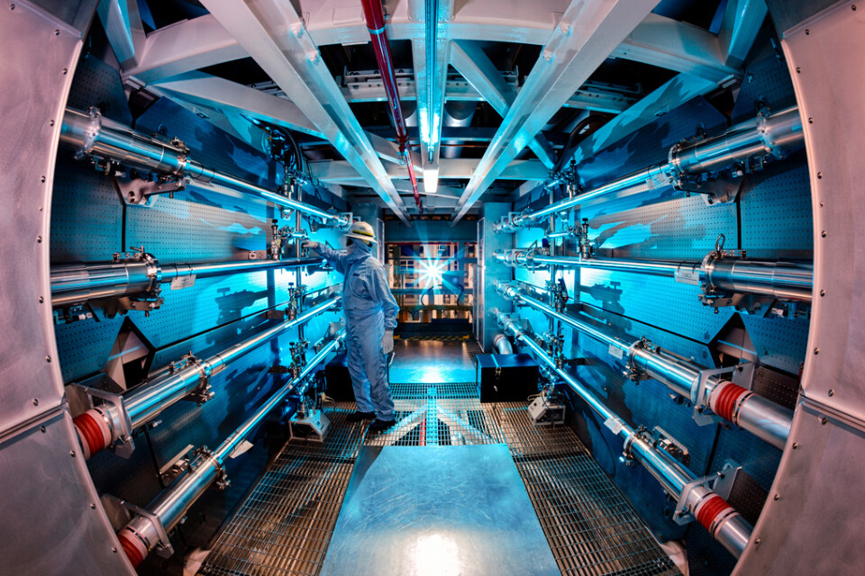 Bild Lawrence Livermore National Laboratory, där en tekniker ser över optiken i fusionslaboratoriet. Arkivbild.