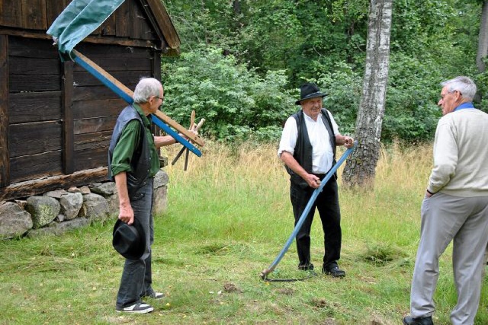 Karl-Lennart Svensson i mitten visade besökarna hur man hanterar en lie. Att låna ut verktyget var dock inte aktuellt under arrangemanget i Broby hembygdsgård. Foto: Markus Danielsson