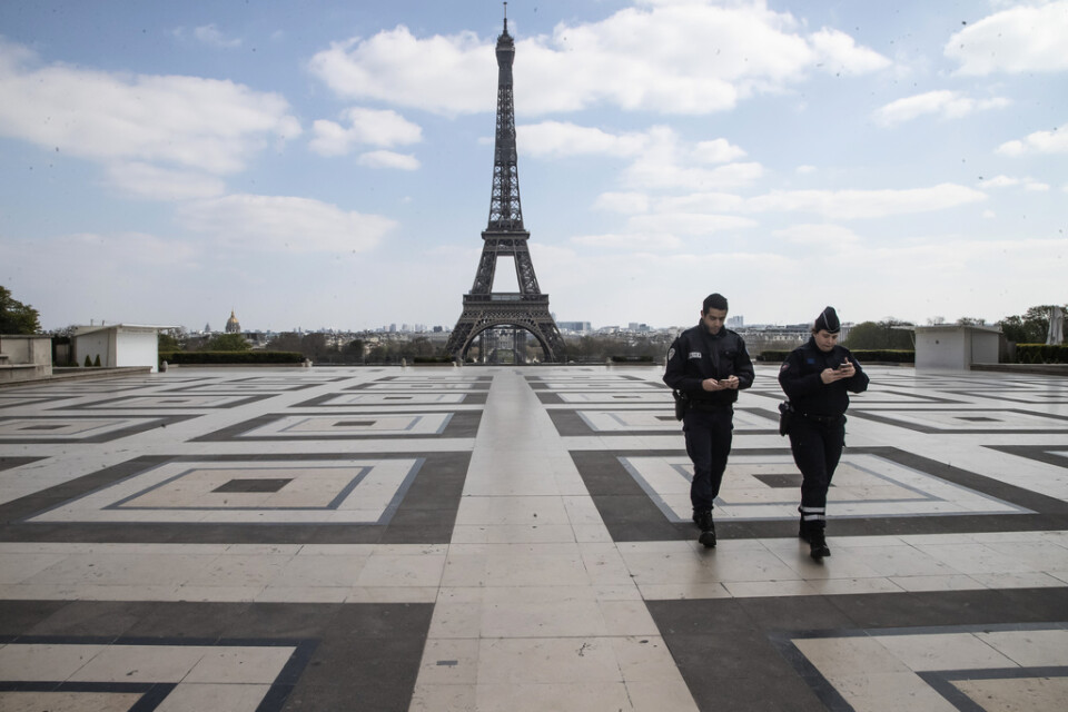 Poliser håller koll på att människor håller sig hemma, vid Trocadéro i Paris, med Eiffeltornet i bakgrunden.