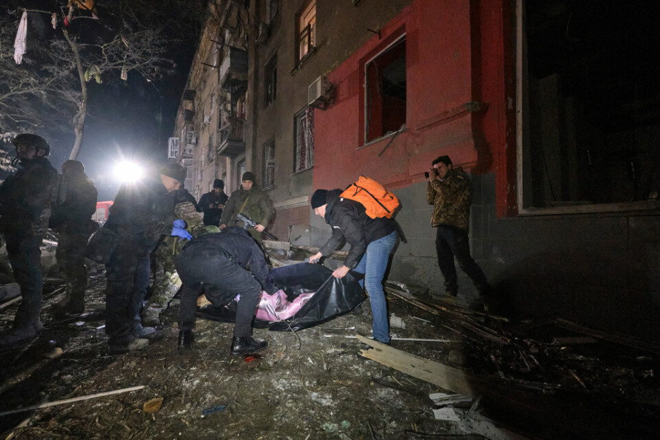 Ukrainska poliser vid det förstörda lägenhetshuset i Kramatorsk placerar ett av dödsoffren i en säck.
