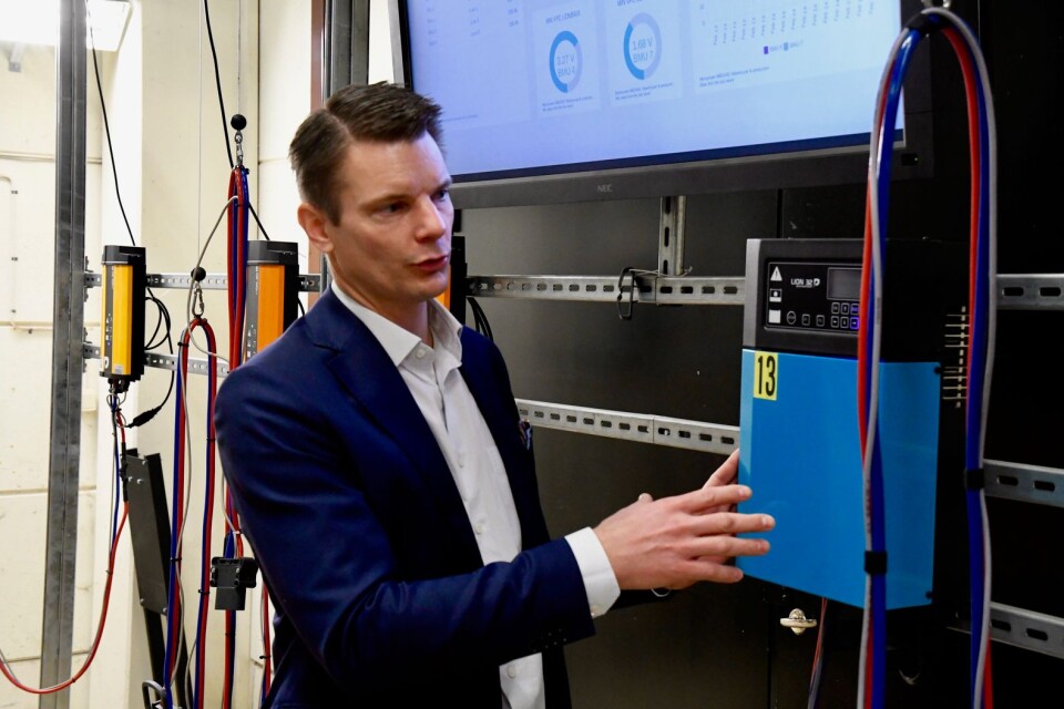 Torbjörn Gustafsson visar en batteriladdare och på skärmen bakom informationen som kan tas fram med hjälp av det nyutvecklade systemet.