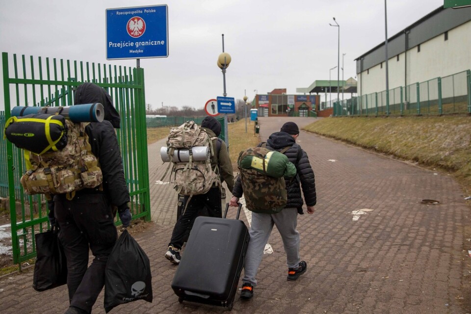 Män med stridsutrustning på väg in i Ukraina från polska gränsen i Medyka under lördagen.