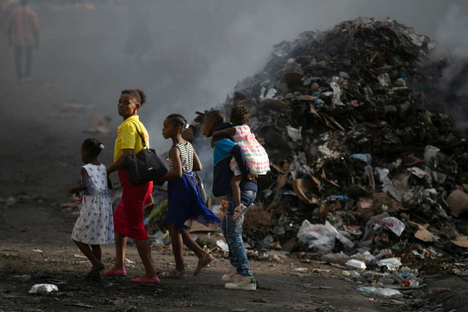 En familj framför en rykande sophög i Port-au-Prince i onsdags.