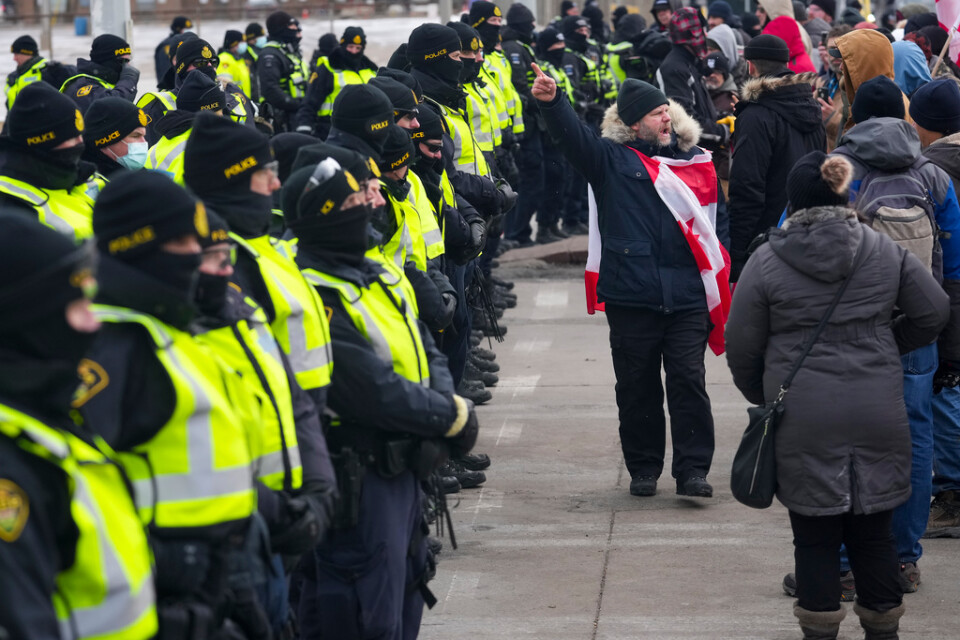En demonstrant skriker till de kanadensiska poliserna samtidigt som andra demonstranter gör sig redo att lämna Ambassador Bridge, som går mellan Detroit i USA och staden Windsor i Kanada.