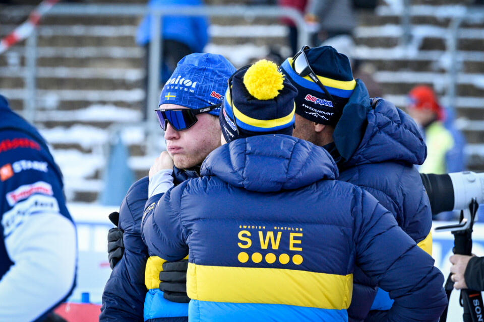 Sveriges Sebastian Samuelsson (vänster) grät och tröstades av tränarna Jean-Marc Chabloz (höger) och Johannes Lukas efter målgång i onsdagens mixedstafett.