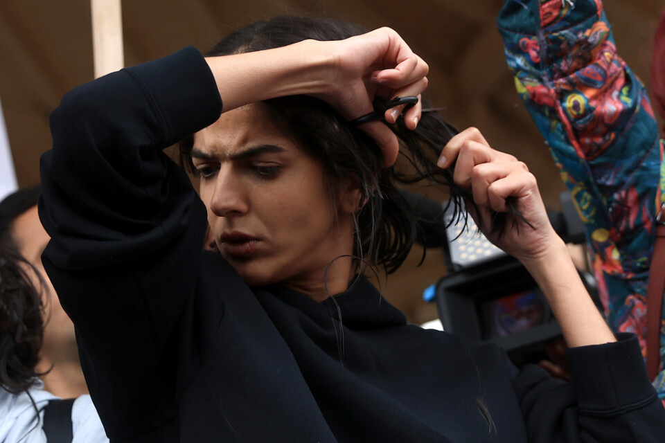 En kvinna klipper sitt hår under demonstrationen i Paris.