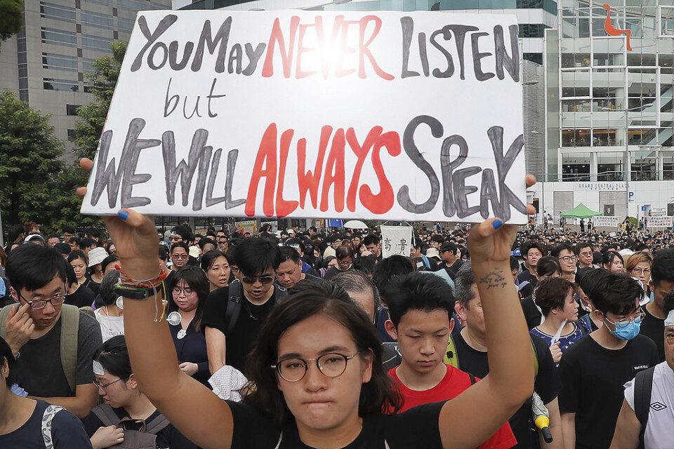 "Du kanske aldrig lyssnar men vi kommer alltid att tala", står det på skylten som en kvinna håller upp under söndagens protester i distriktet Sha Tin i Hongkong.