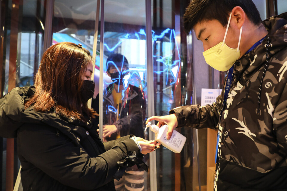 Kunder på ett köpcenter i Wuhan får handsprit av personalen. Arkivbild.