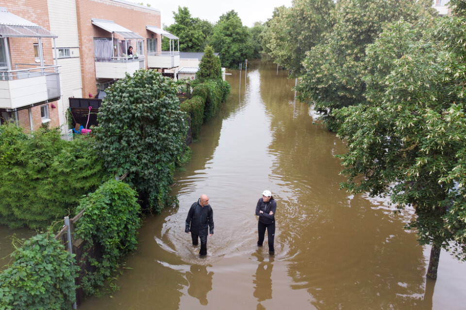 Två personer vadar genom översvämning vid ett bostadsområde vid Södra Kungsvägen i Gävle.