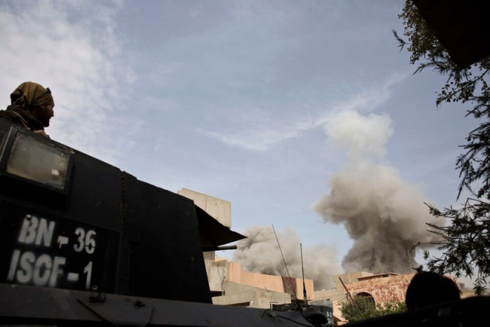 En iraksik soldat betraktar läget när röken stiger upp efter ett bombanfall i Mosul i Irak 12 april i fjol utfört av den USA-ledda koalitionen. Anfallet riktades mot platsen där en bilbomb precis sprängts, medan man försökte återta en stadsdel från IS-soldater.
