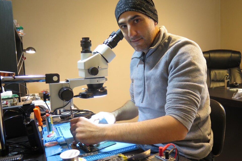 Houssam Sidani använder mikroskop och särskilda instrument när han lagar och byter ut mobiltelefoners elektroniska komponenter. Vissa delar är mindre än riskorn. Han har arbetat med datorservice, mobilreparationer och IT i allmänhet i nästan 20 år. Foto: Oskar Sandström