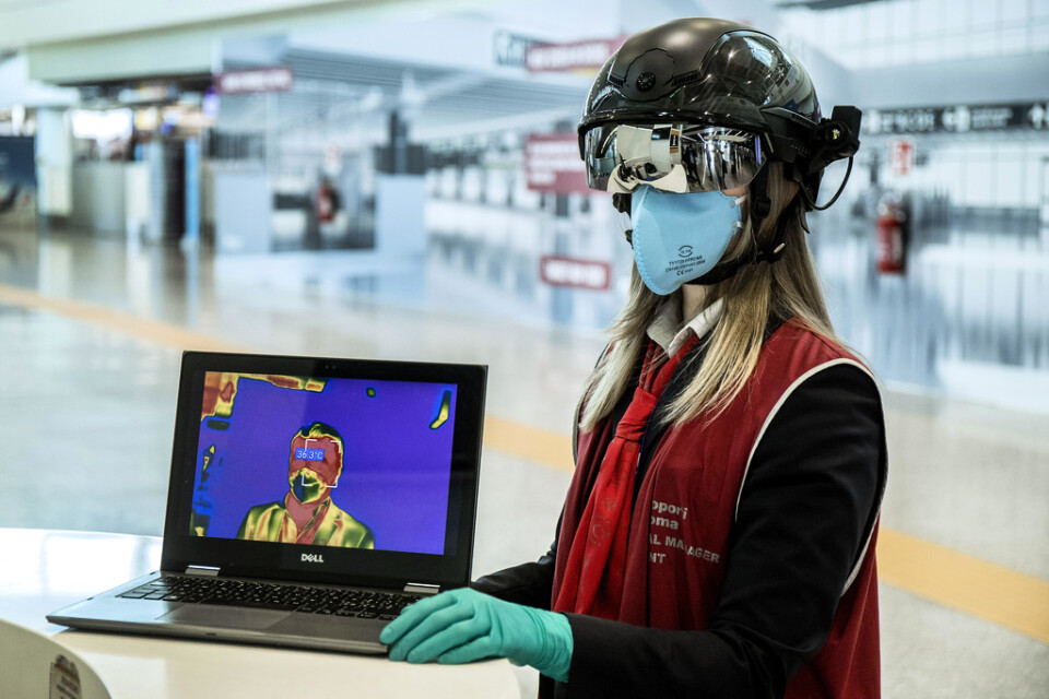 En medarbetare vid Romflygplatsen Leonardo da Vinci använder sig av en så kallad smarthjälm för att mäta kroppstemperaturen hos passagerare.