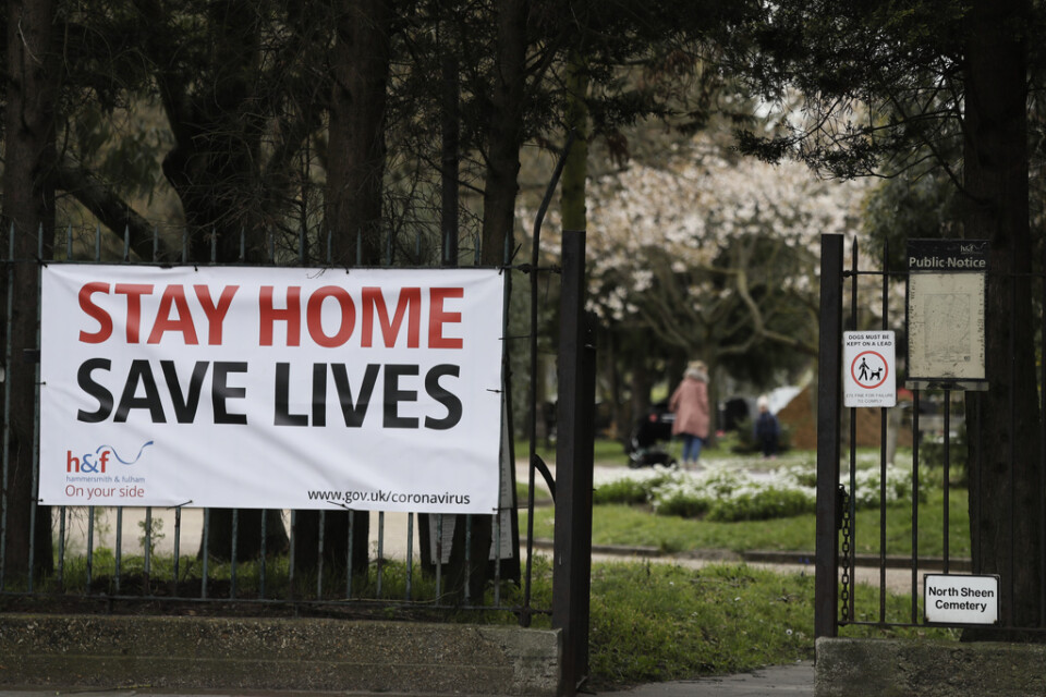 En stor skylt med ett tydligt budskap – stanna hemma, rädda liv – vid en park i London.