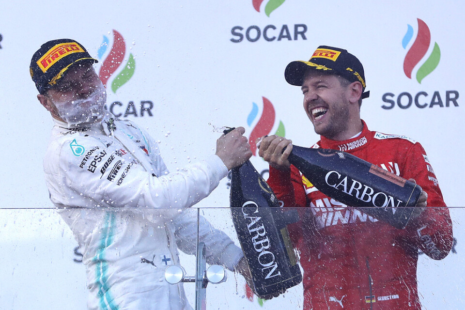 Trean Sebastian Vettel, Ferrari, ser till att vinnaren Valtteri Bottas, Mercedes, får smaka champagne.