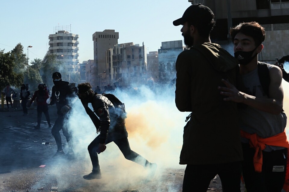 Regeringskritiska demonstranter flyr undan säkerhetsstyrkornas tårgas vid protester i Bagdad på söndagen.