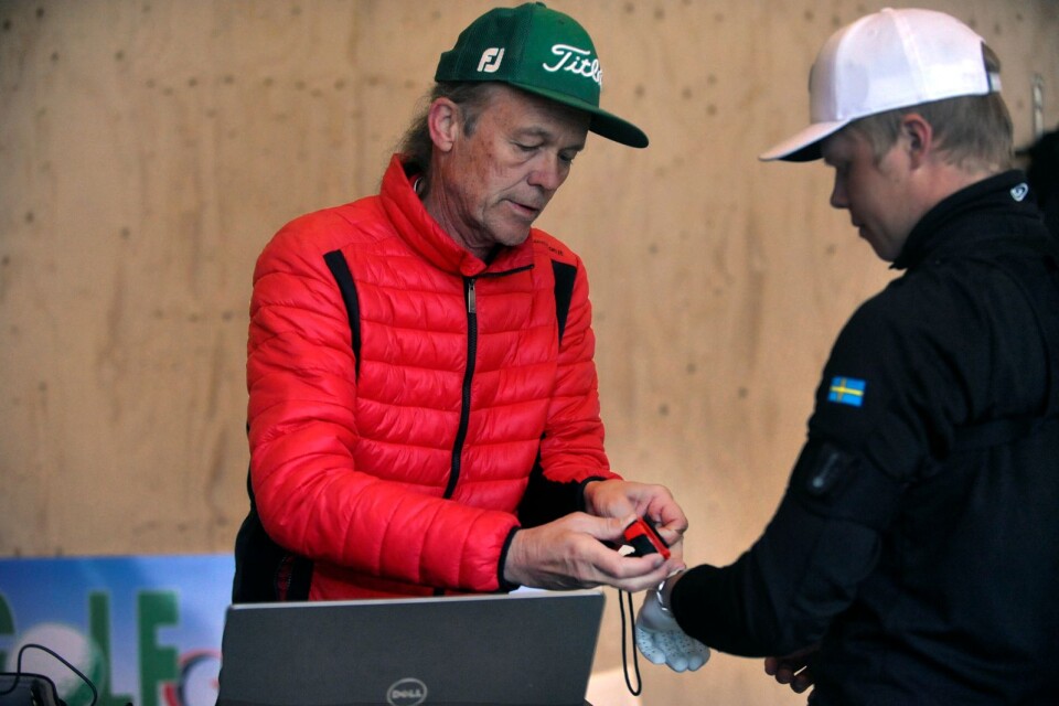 Håkan Fransson klär på Oscar Toreld en sensor på handen, så att han kan analysera Oscars sving från en data.
