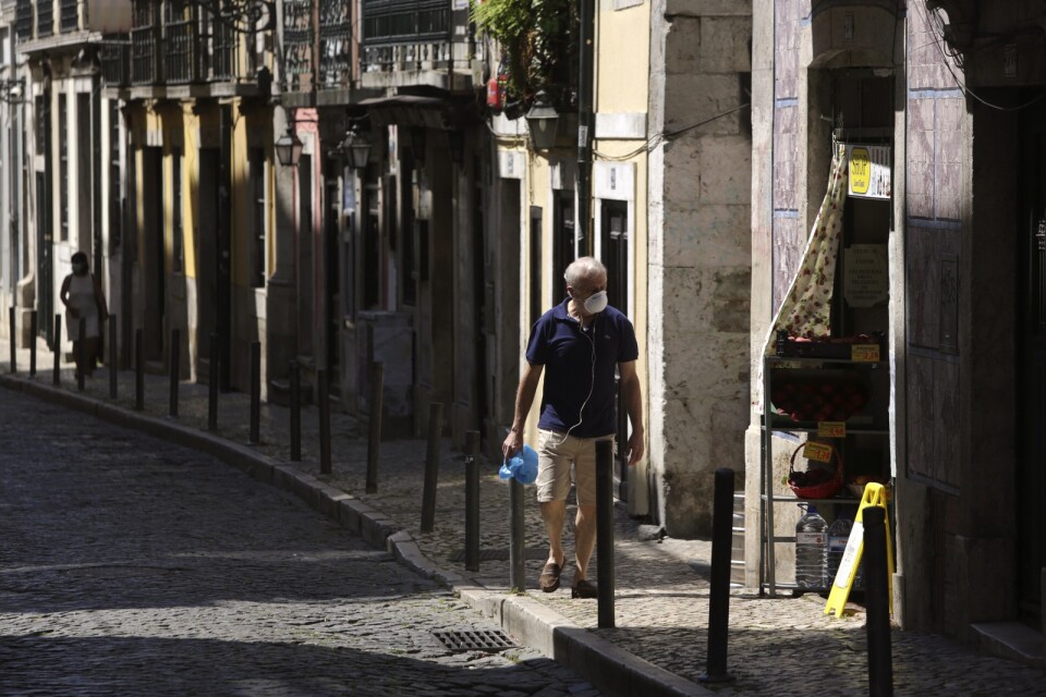 En man iförd munskydd promenerar längs en gata i Portugals huvudstad Lissabon. Arkivbild.