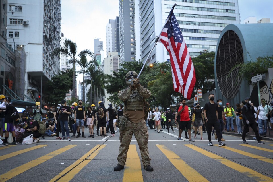 En demonstrant utklädd till militär håller en amerikansk flagga under demokratiprotester i Hongkong i augusti 2019.