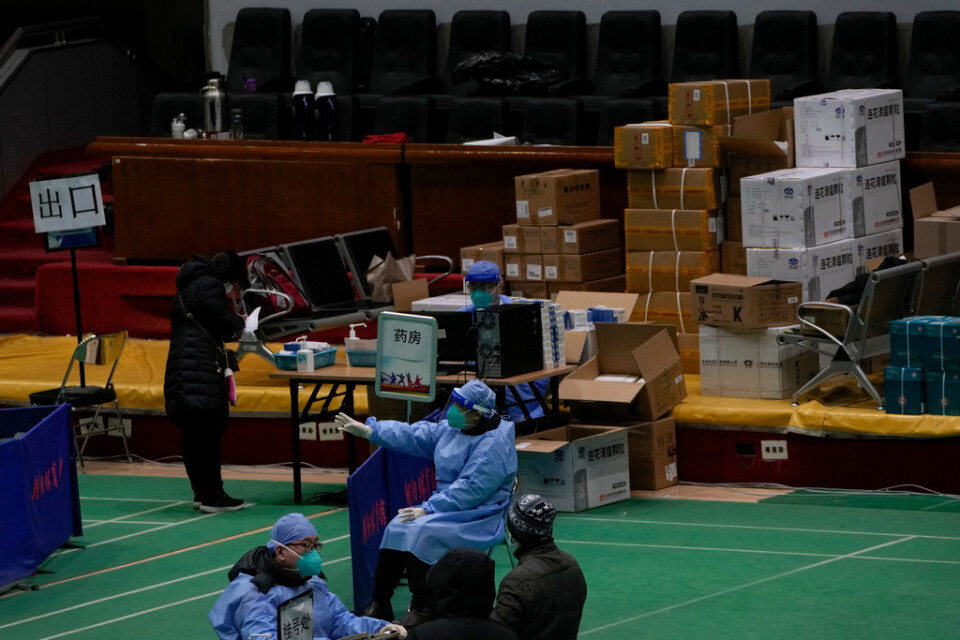 Invånare hämtar läkemedel och annat som kan hjälpa, på en så kallad feberklinik som inrättats i en gymnastiksal i Peking.