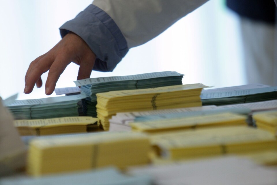 Väljare plockar valsedlar i en röstningslokal för förtida röstning.
