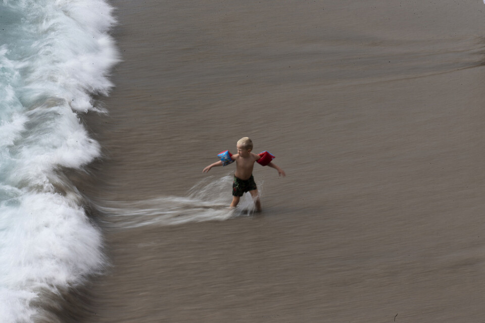 Ett barn leker i vågorna på en strand i Spanien – dock inte i Zahara de los Atunes. Arkivbild.
