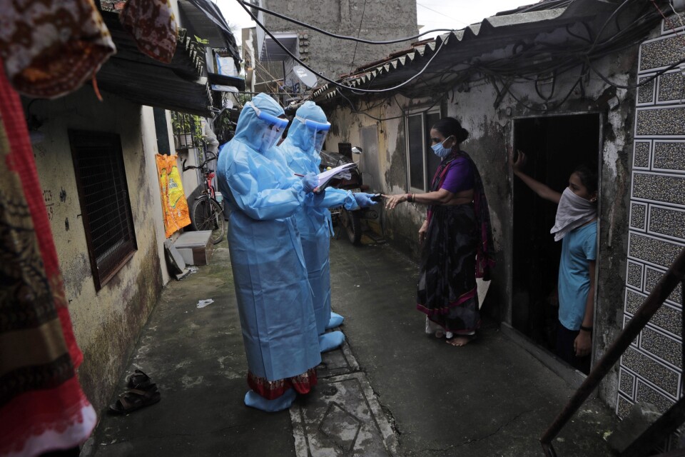 Indiska hälsoarbetare covid-screenar boende i ett fattigt område i staden Bombay (Mumbai).