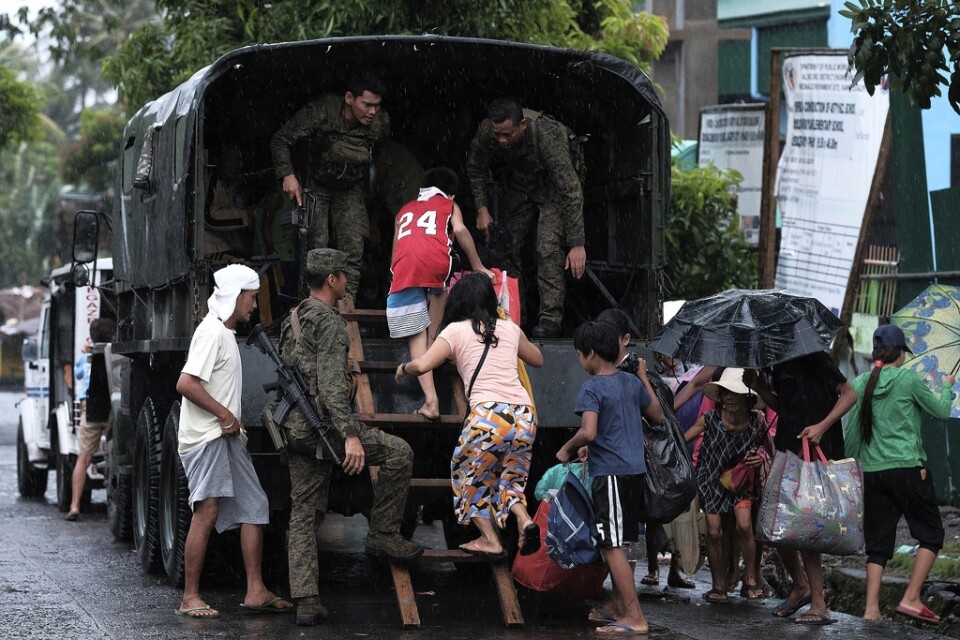 Boende i Legazpi i provinsen Albay klättrar upp i ett militärfordon för att bli evakuerade till säkrare platser.